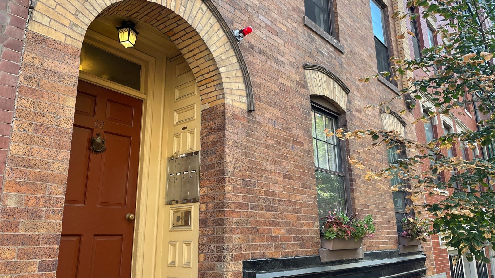brick multi-story townhouse with red door under a rounded archway.