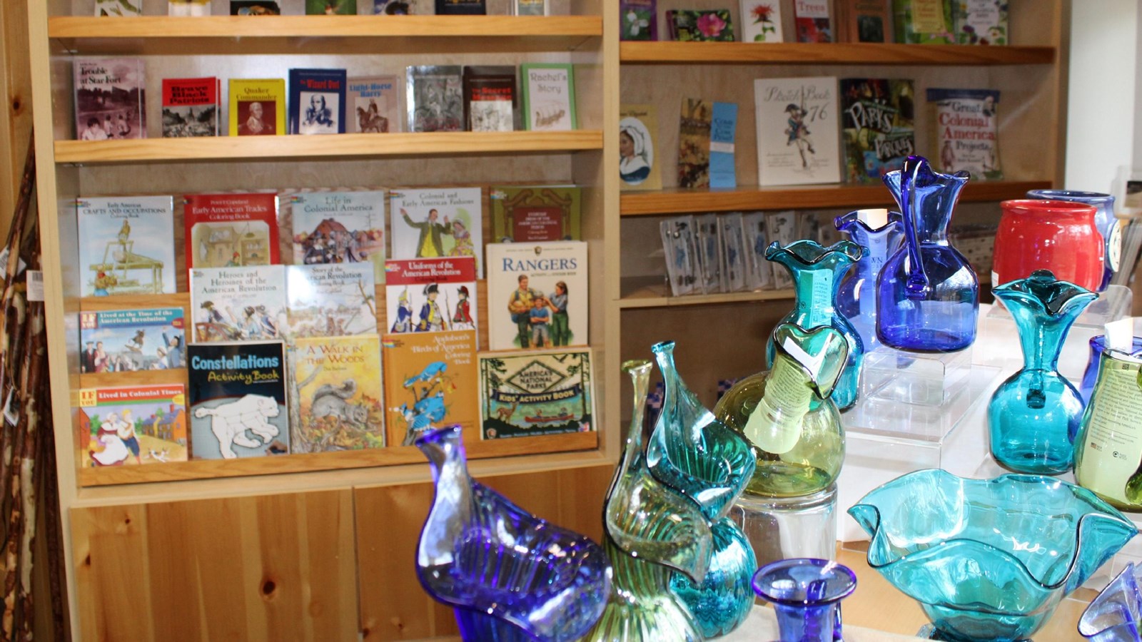 Colorful colonial glassware in front of shelves of books.
