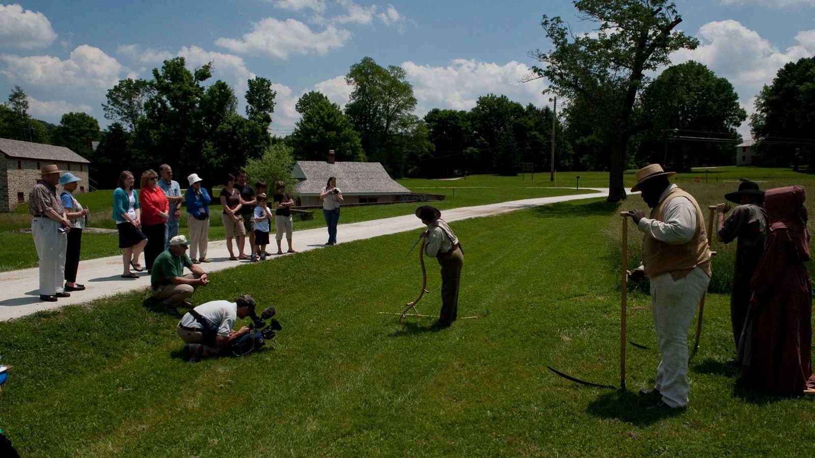 Living historians talk to a group of visitors along the farm lane.