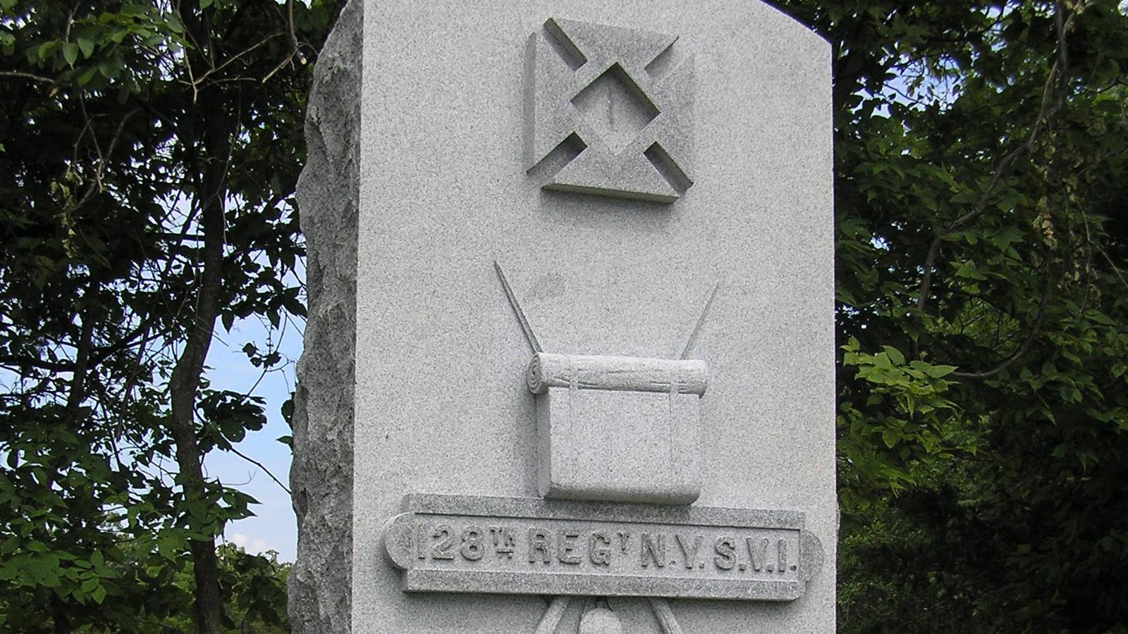A tall stone lozenge with a square cross and arms is inscribed 128th REGt NYSVI.
