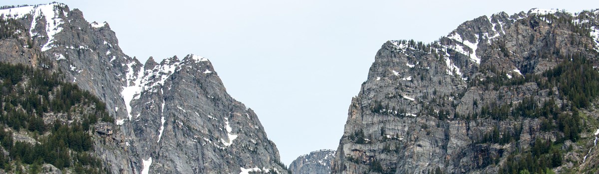 A rocky mountain canyon sits across a calm lake.