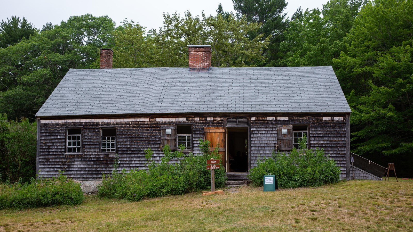 Wooden structure with two chimneys surrounded by a yard