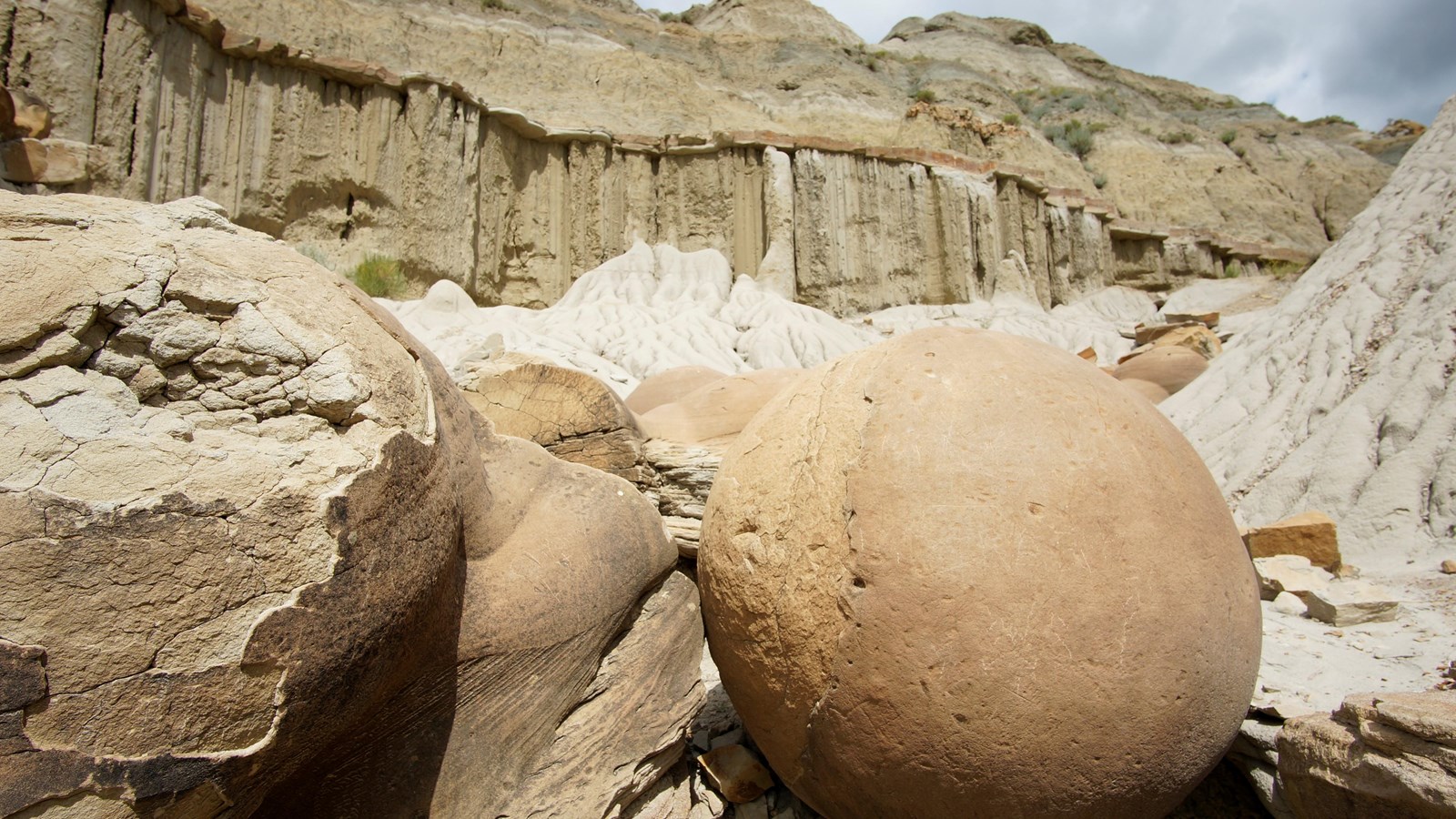 Two large, round stones take up the majority of the image, with more behind, and a butte in the back