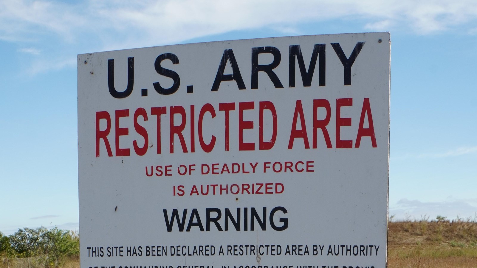 A white warning sign with black and red lettering indicating the severe penalty for trespass