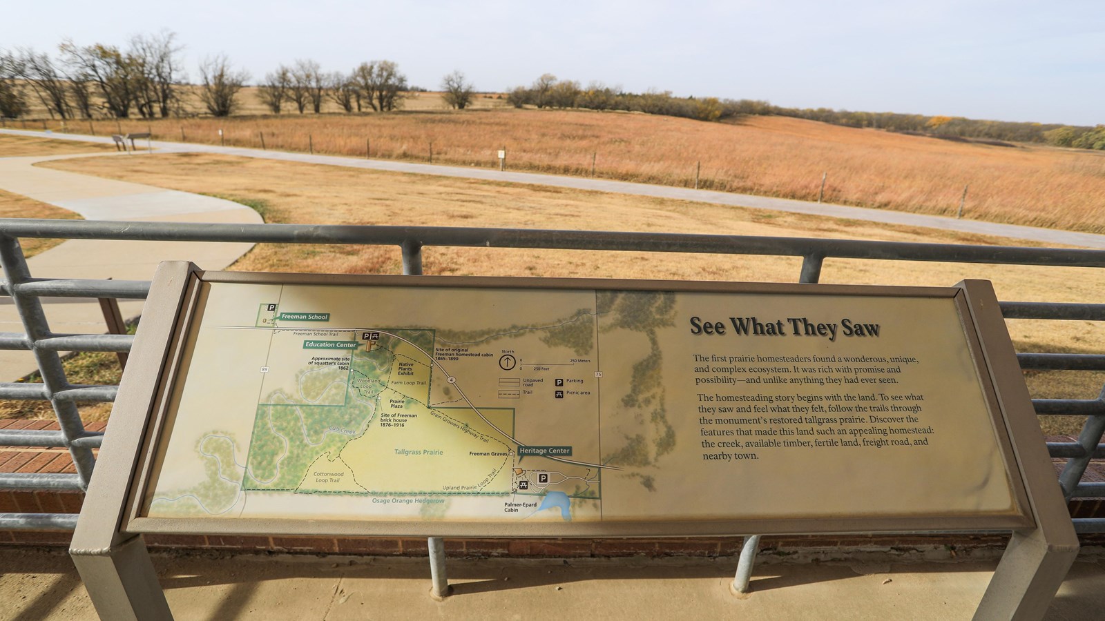 Informational sign stands in front of restored tallgrass prairie and an Osage orange hedgerow.