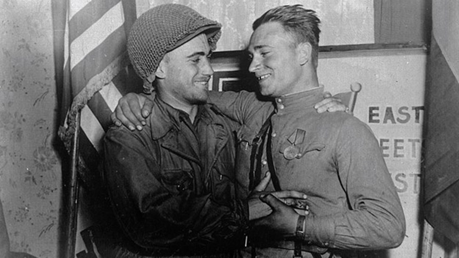 Two men in different military style uniforms embrace
