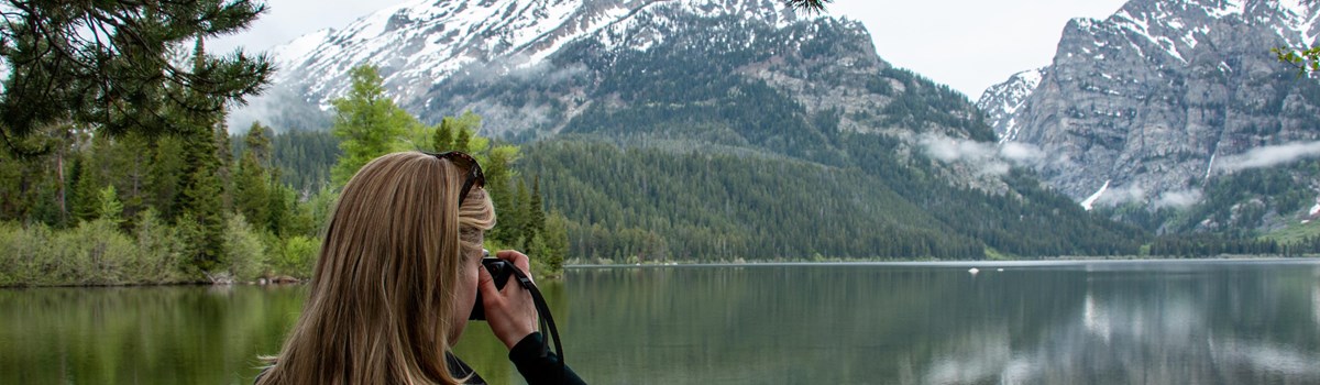 A woman take a picture beside a lake.