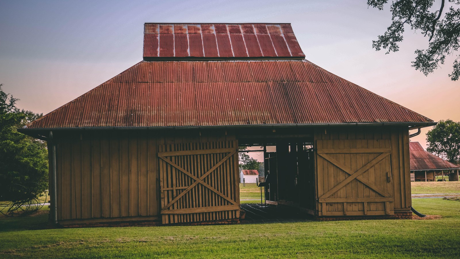 A wooden building with two large doors and a metal roof.