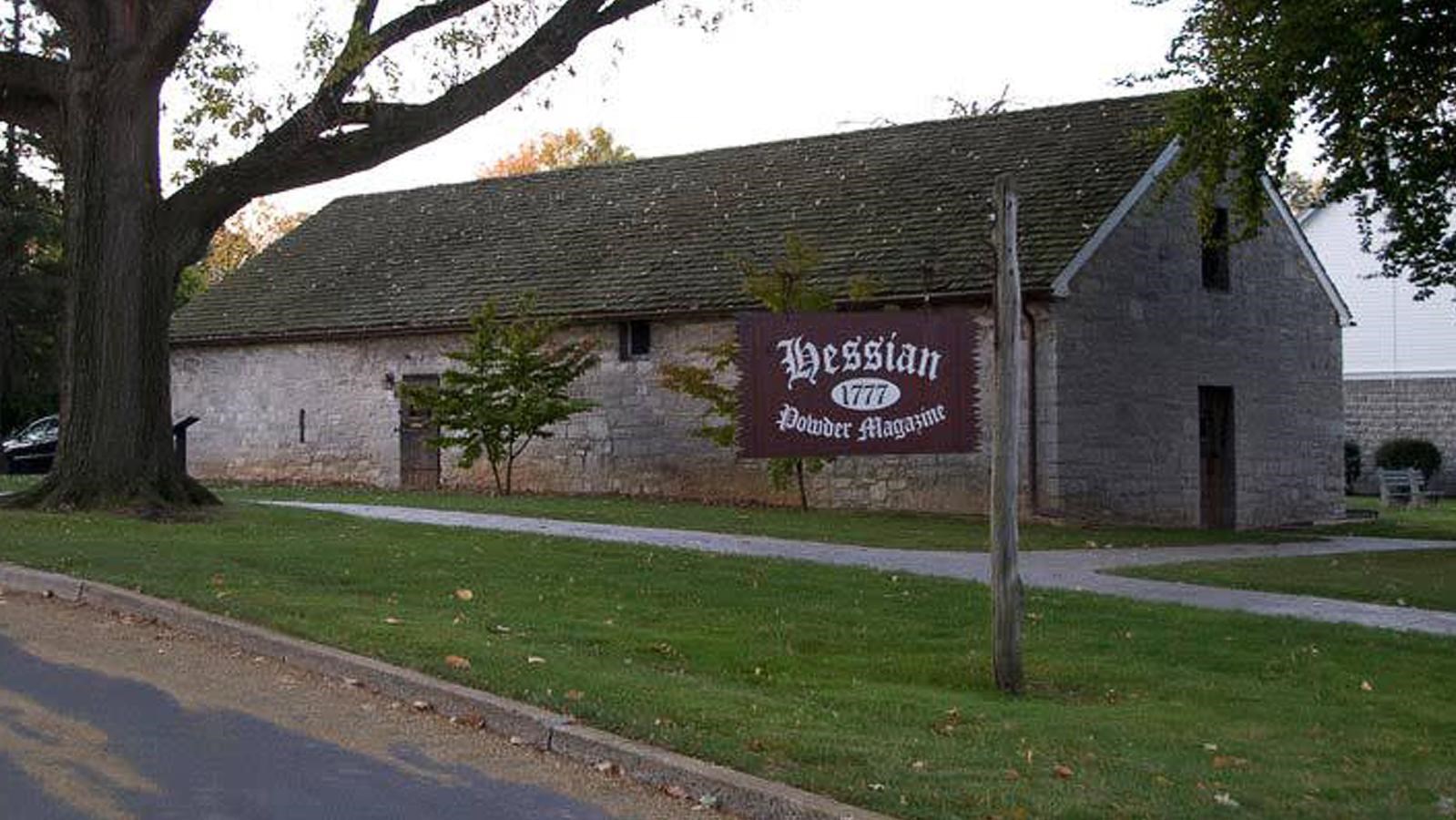 A long one-story grey stone building with a wooden sign reading