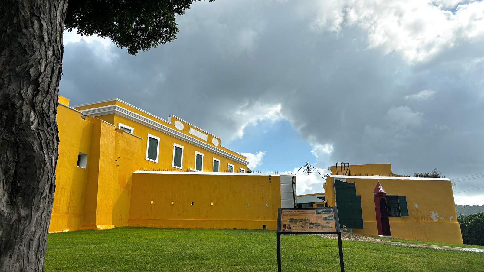 Photo of yellow fort taken from under a tree with coudy sky.