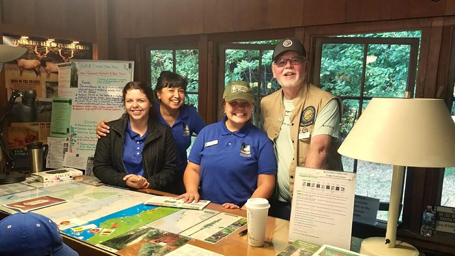 Four staff behind a wooden sales desk.