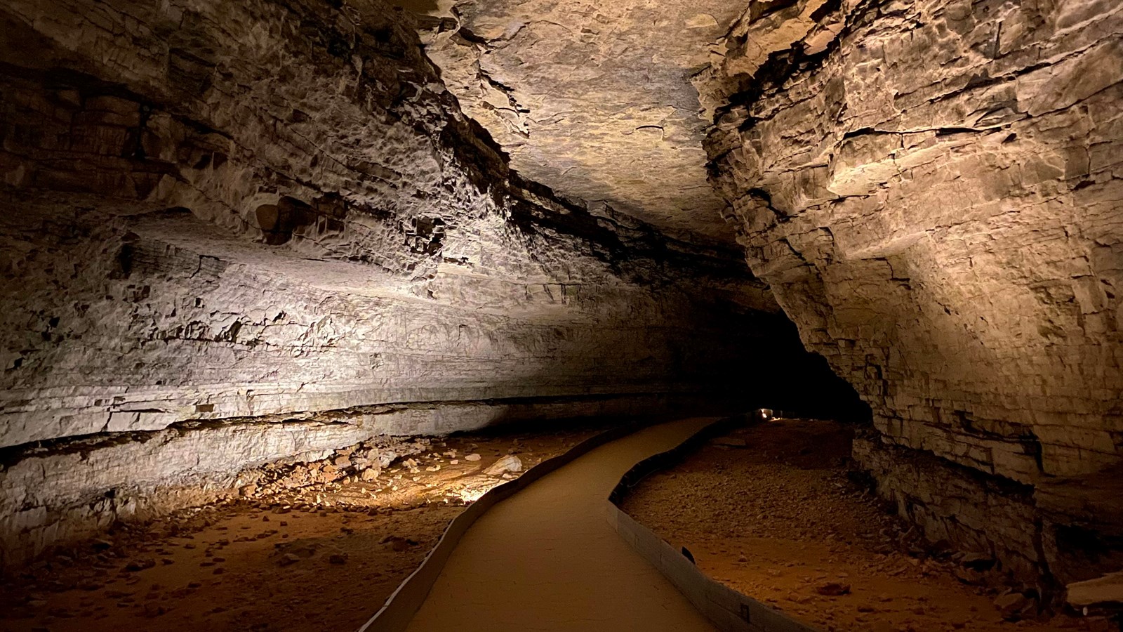 A large open cave passage with a paved trail leading down the middle.