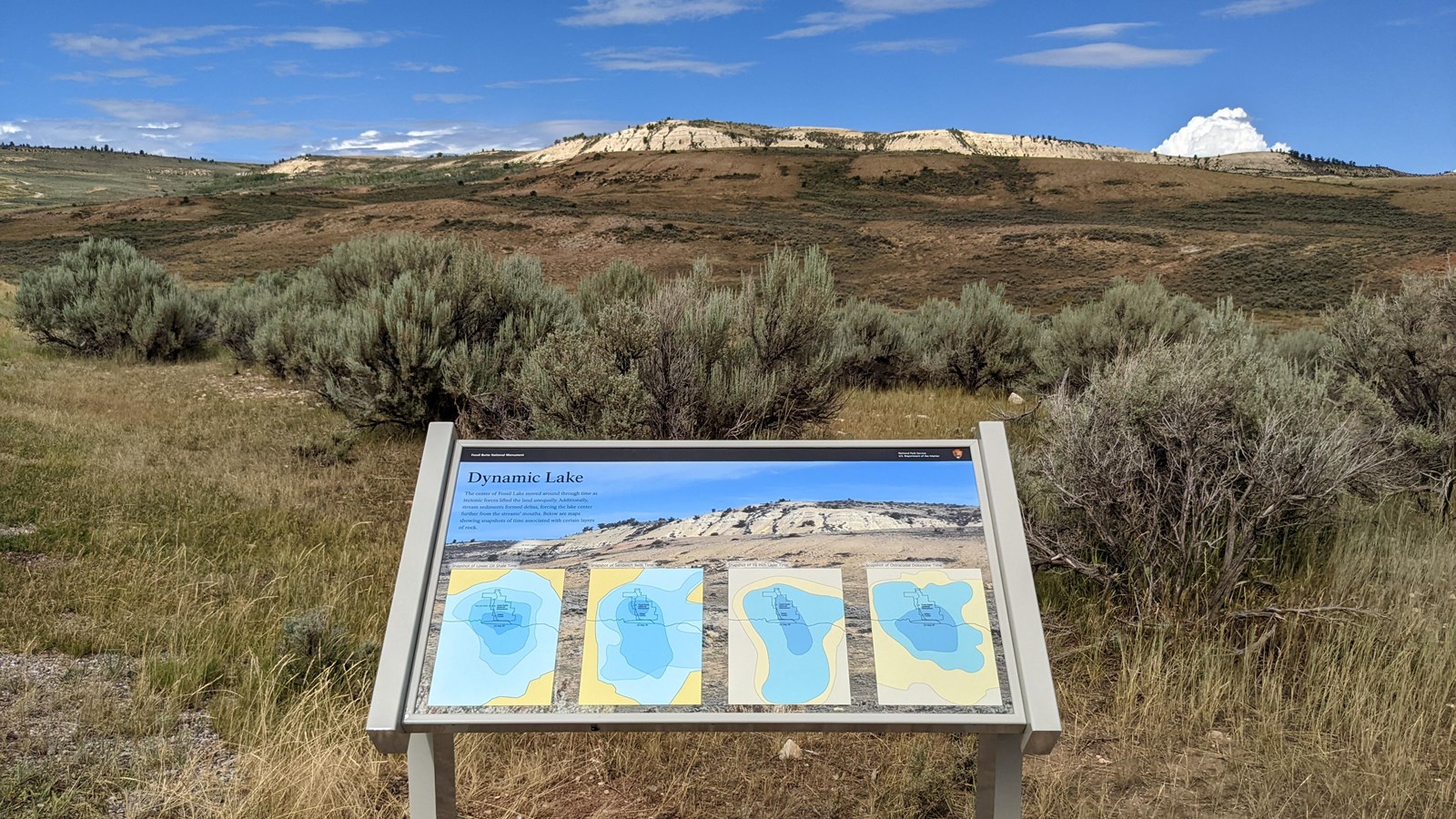 A sign with a photo of the ridge behind and four maps.