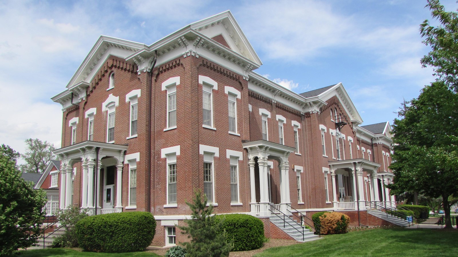 Large, brick Italianate-style headquarters building. Five front bays with small, elaborate porches.