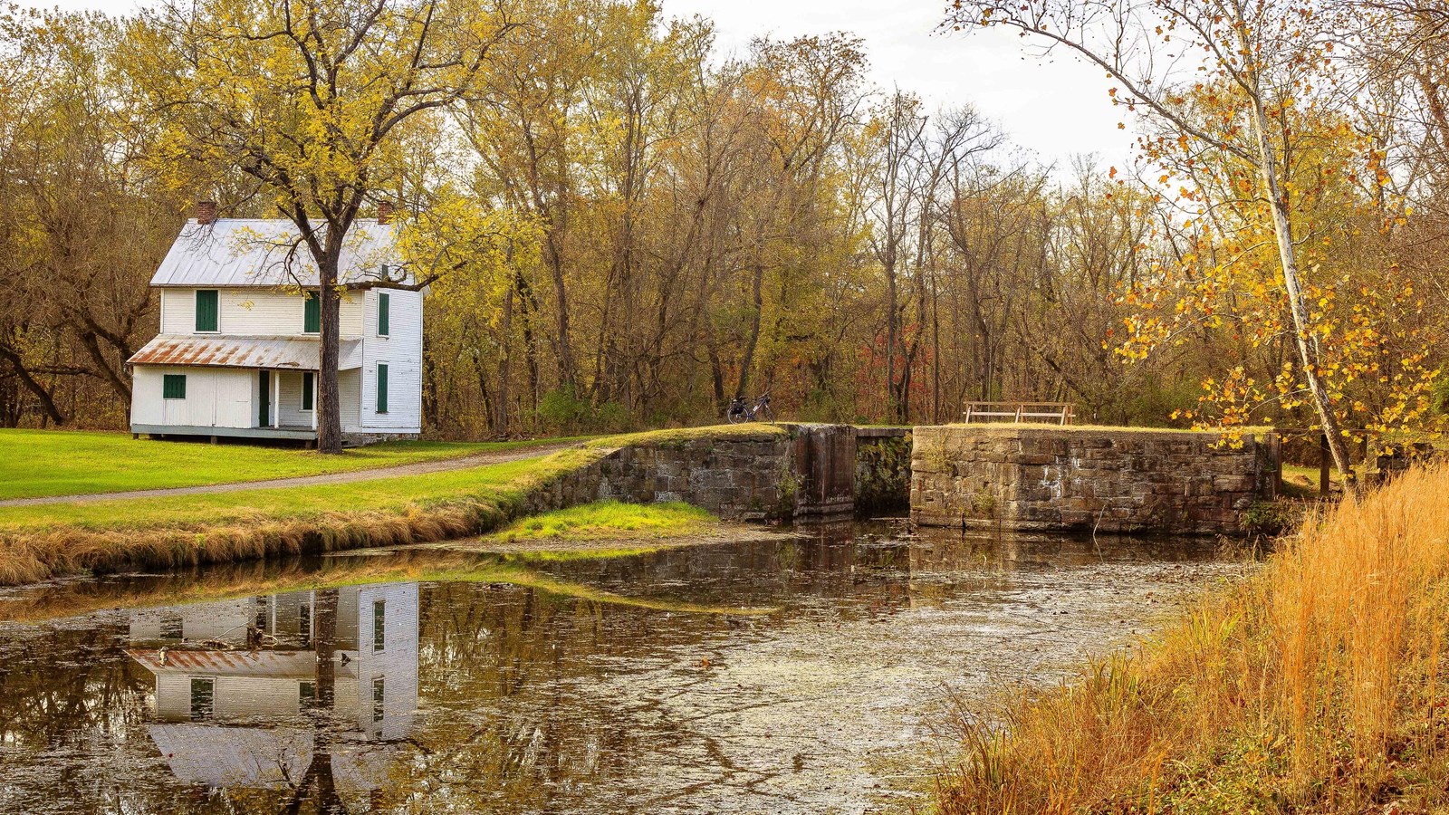 Water runs through lock 71 on the right with the lockhouse on the left, surrounded by fall colors.