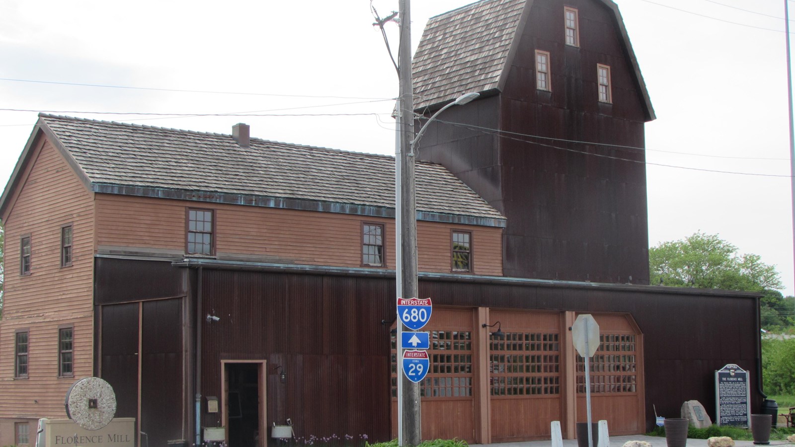 Wood, two-story mill with large elevator shaft on the far right. Three garage door openings on front