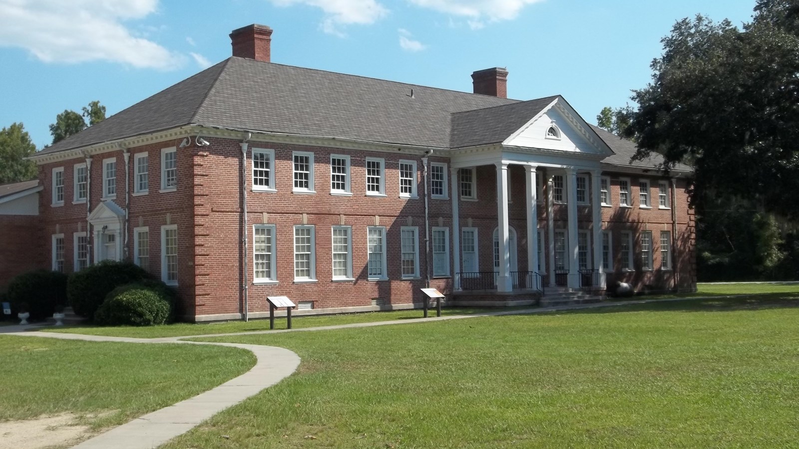 Large, Greco-style university building with green lawn. By Ebyabe, CC BY-SA 3.0