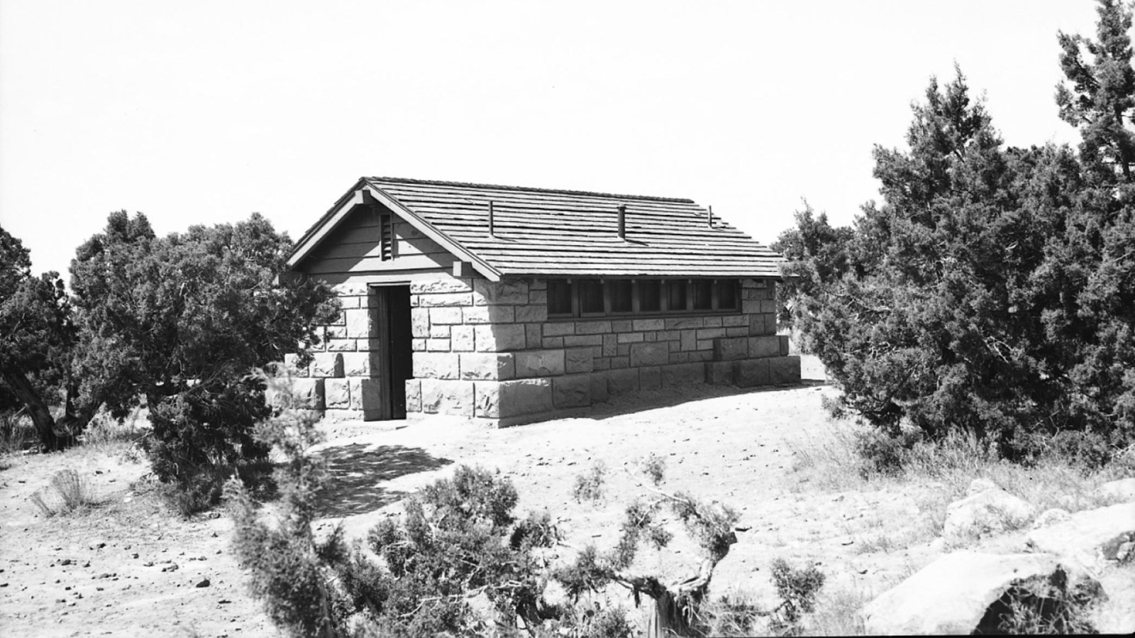 Black and White Image of rectangular building made of large sandstone blocks with a shingle roof.
