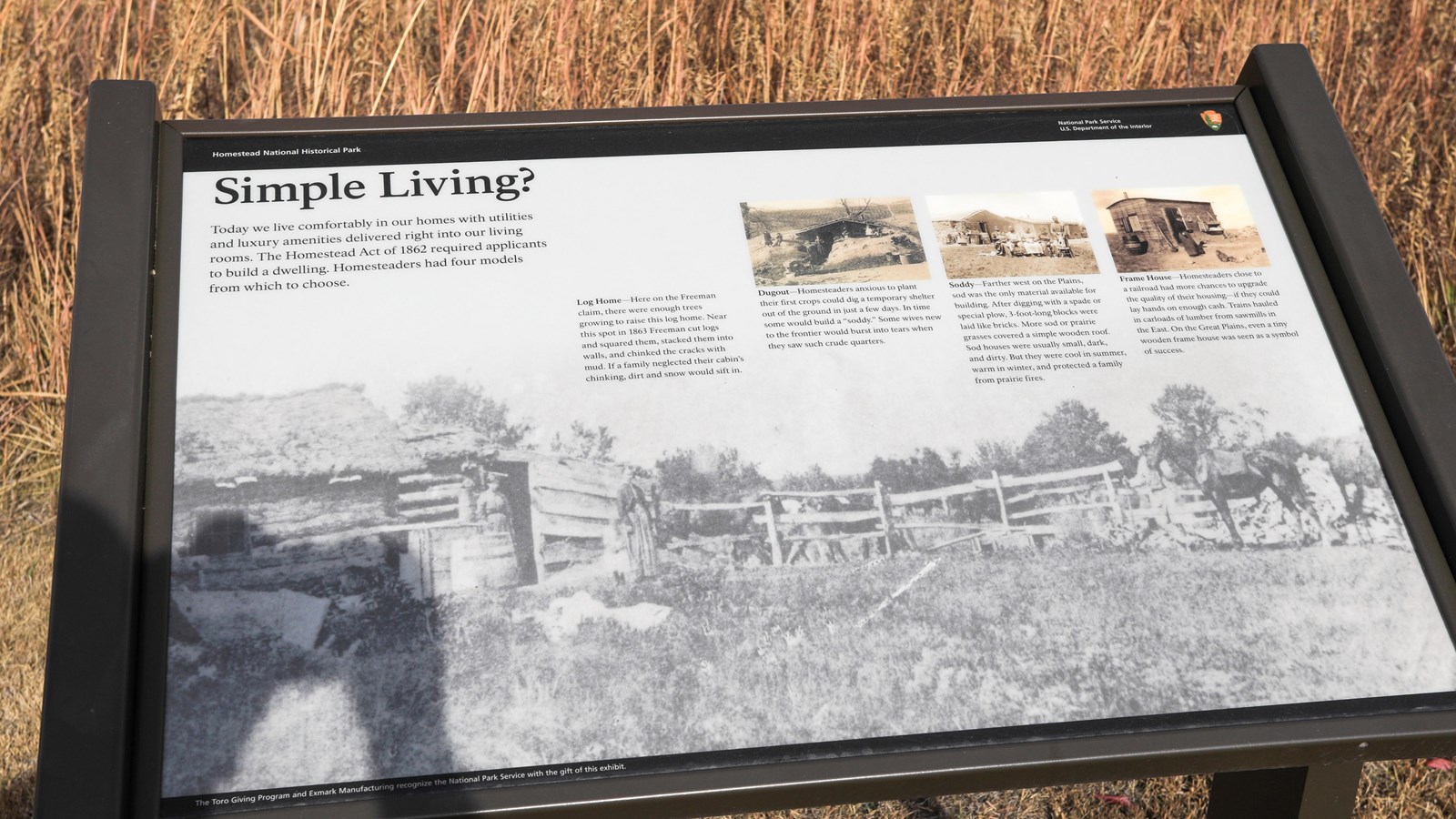 Informational sign stands in front of restored tallgrass prairie.