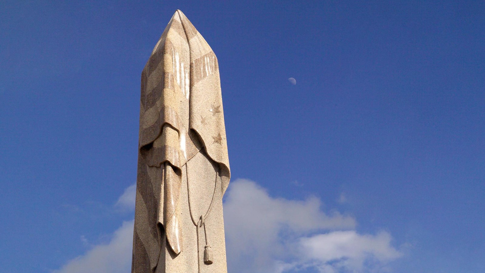 A tall stone column that has been carved to look like an American flag is lying over the top of it. 