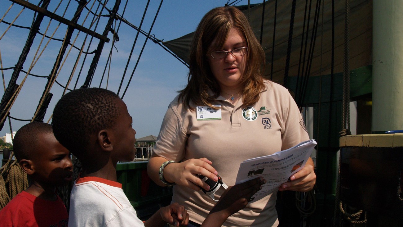 two children show a ranger their answers in the Junior Ranger booklet