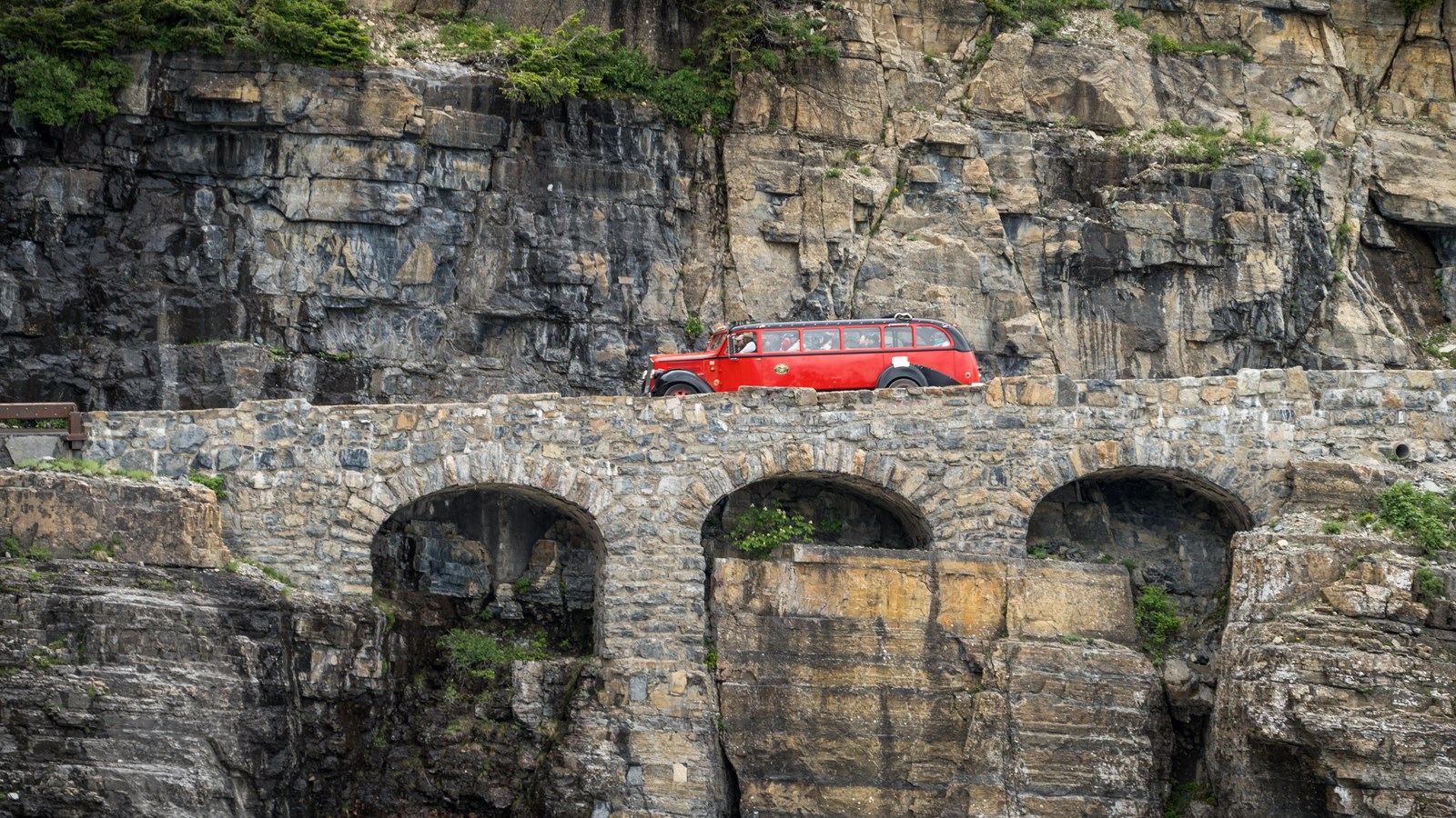 A Red Bus drives across Triple Arches