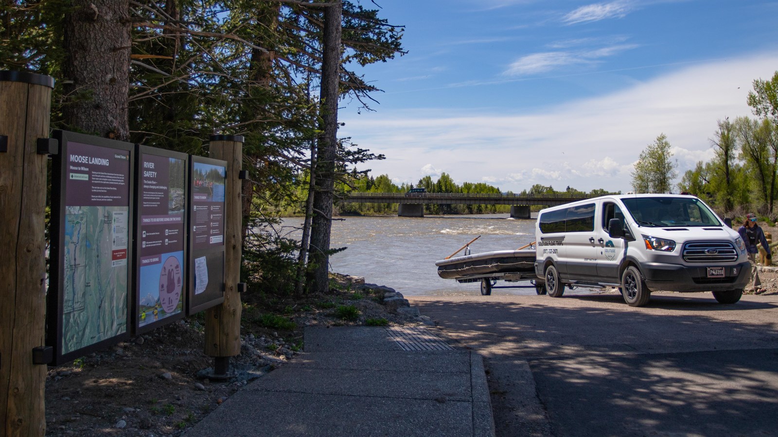 A van pulling a large raft out of the river with informational signs.