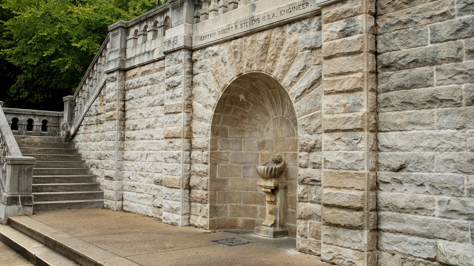 A stone water fountain embedded into a stone walkway 