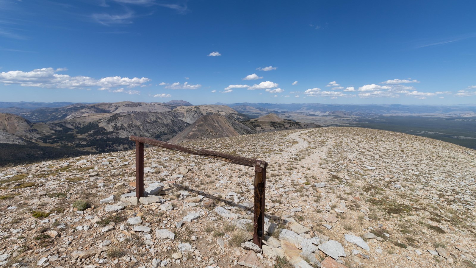 A hitching post at the top of a mountain with a view of other mountains in the distance.