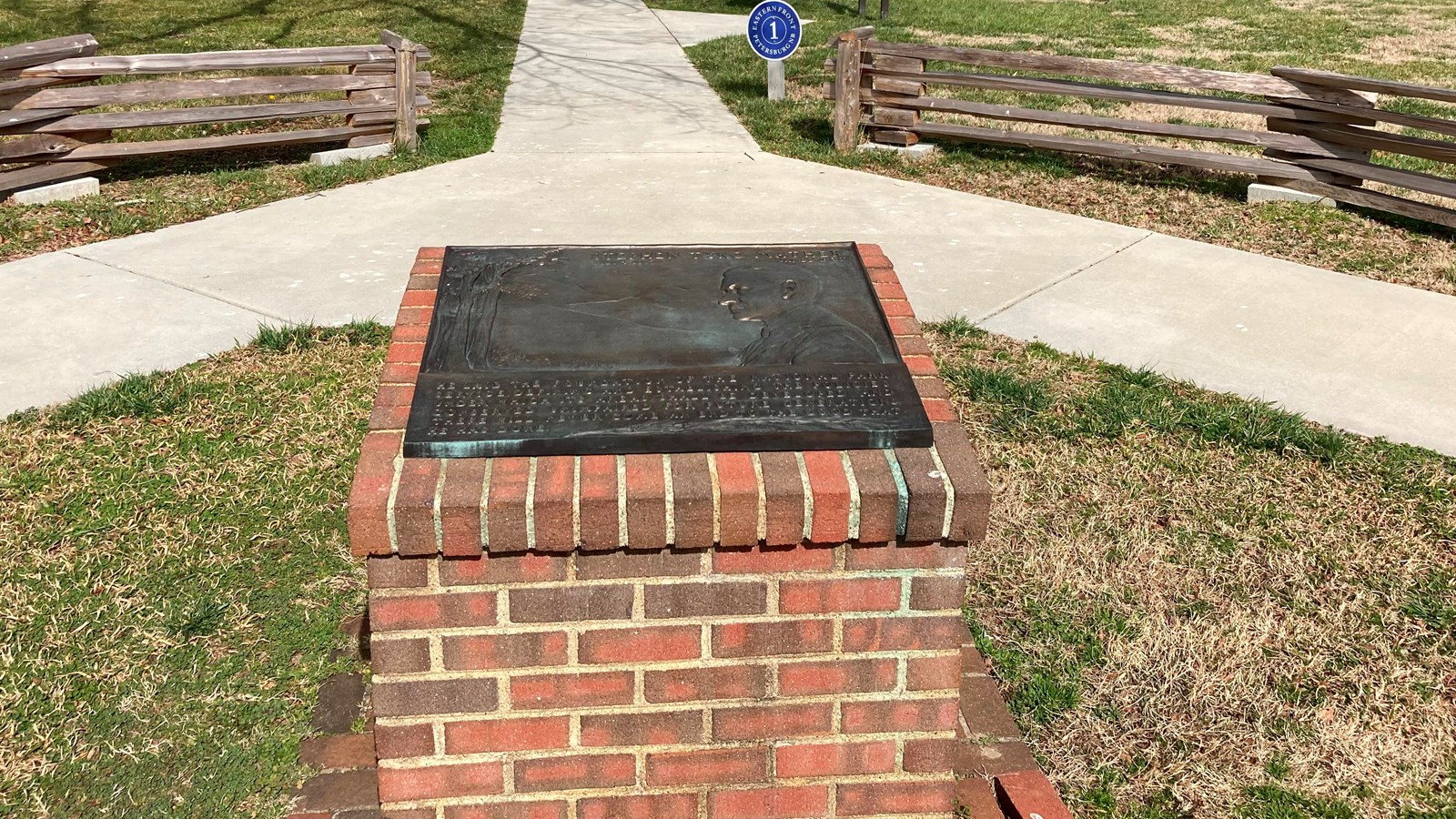 Bronze plaque on a red brick pedestal. 
