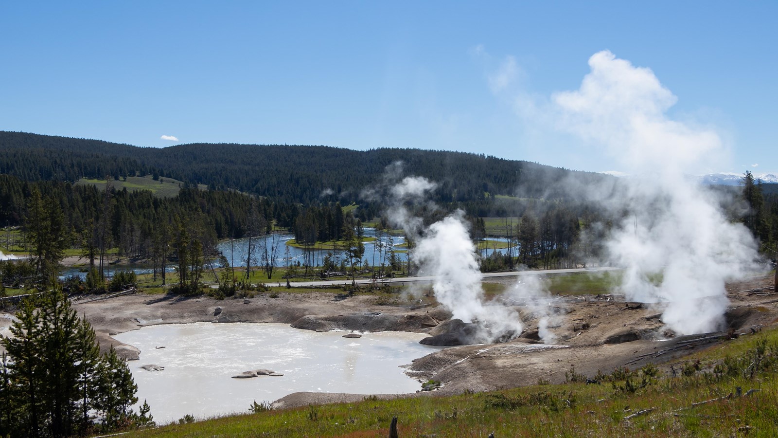Steam rises from fumaroles located next to a large mudpot.