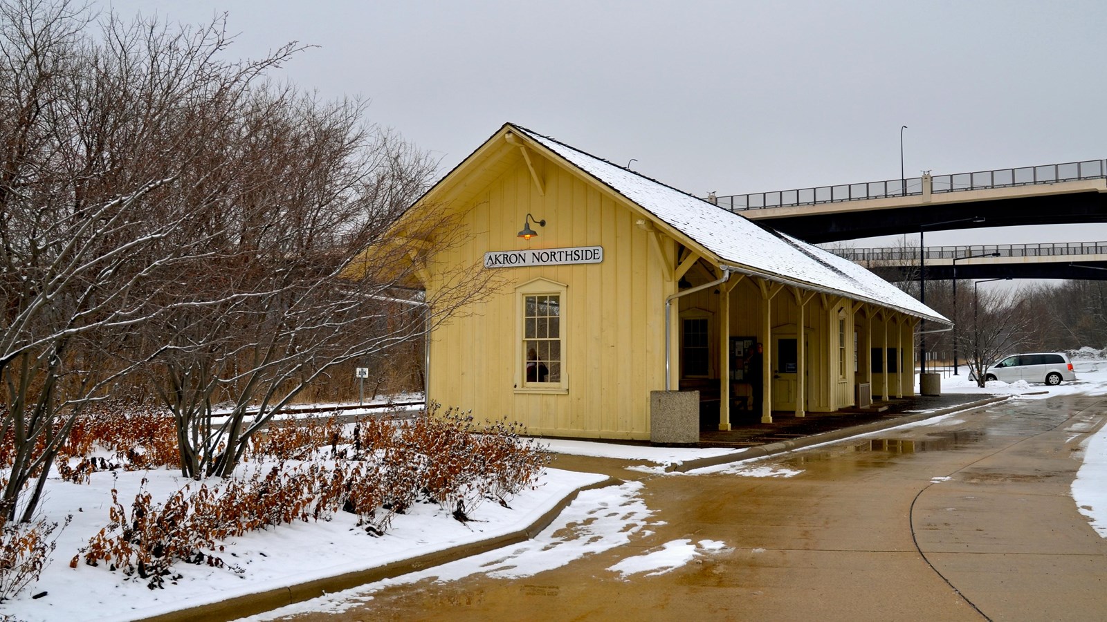 Yellow station with two sheltered waiting areas separated by a ticket booth. Snow on the ground.