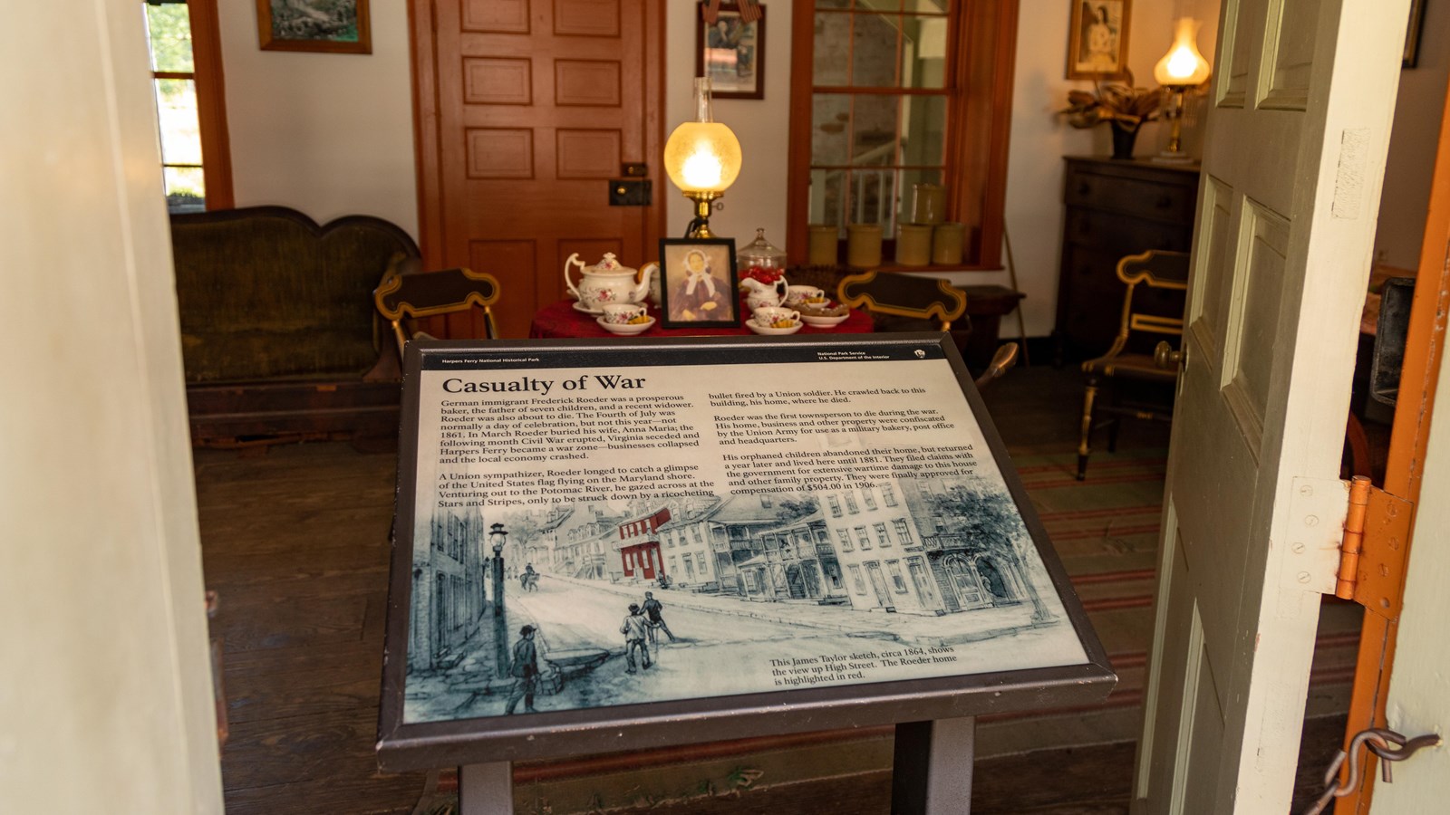 An information panel sits in the doorway of a decorated living room.