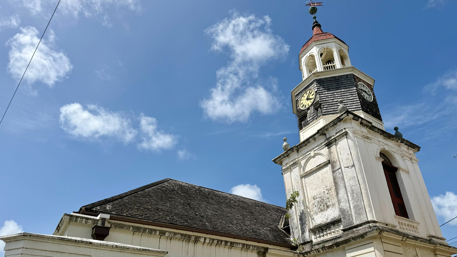 A steeple rising above a church with a clock face
