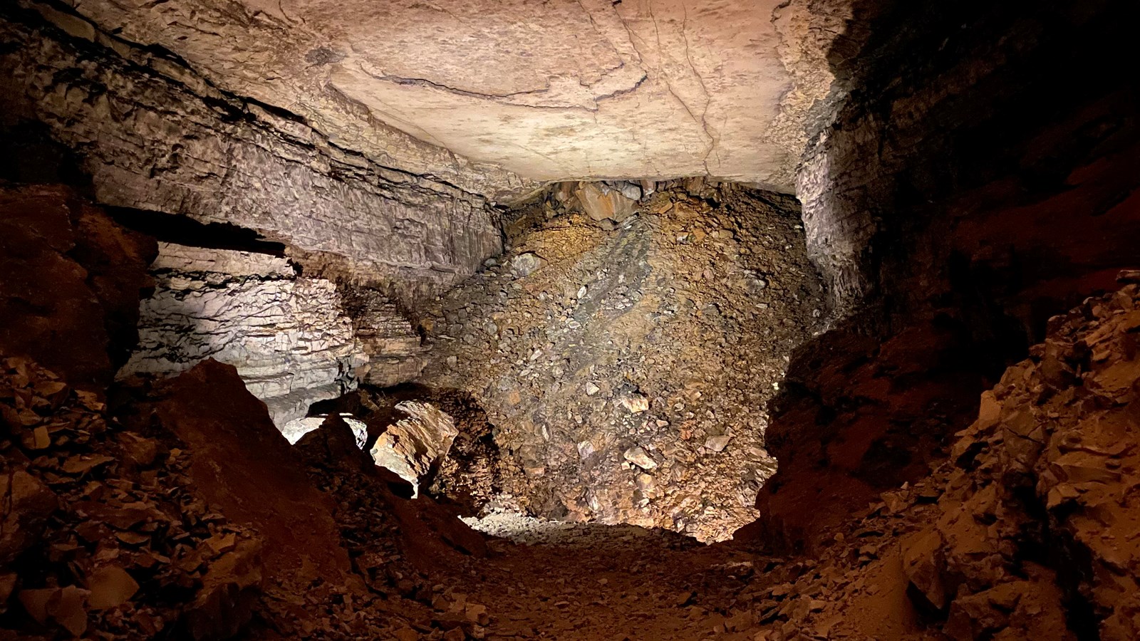 A cave passage leads to a large pile of breakdown.