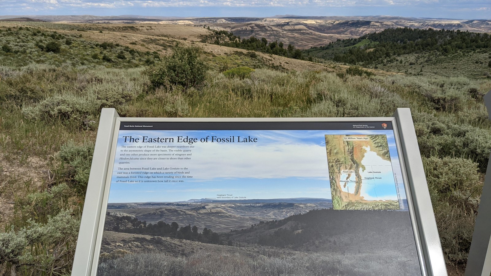 A sign shows a photo of the view behind looking into the distance over ridges and valleys.