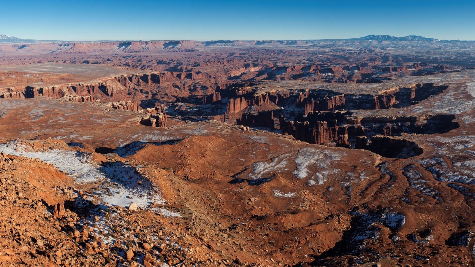White snow dusts the tops of the brown and red canyons from Grand View Point