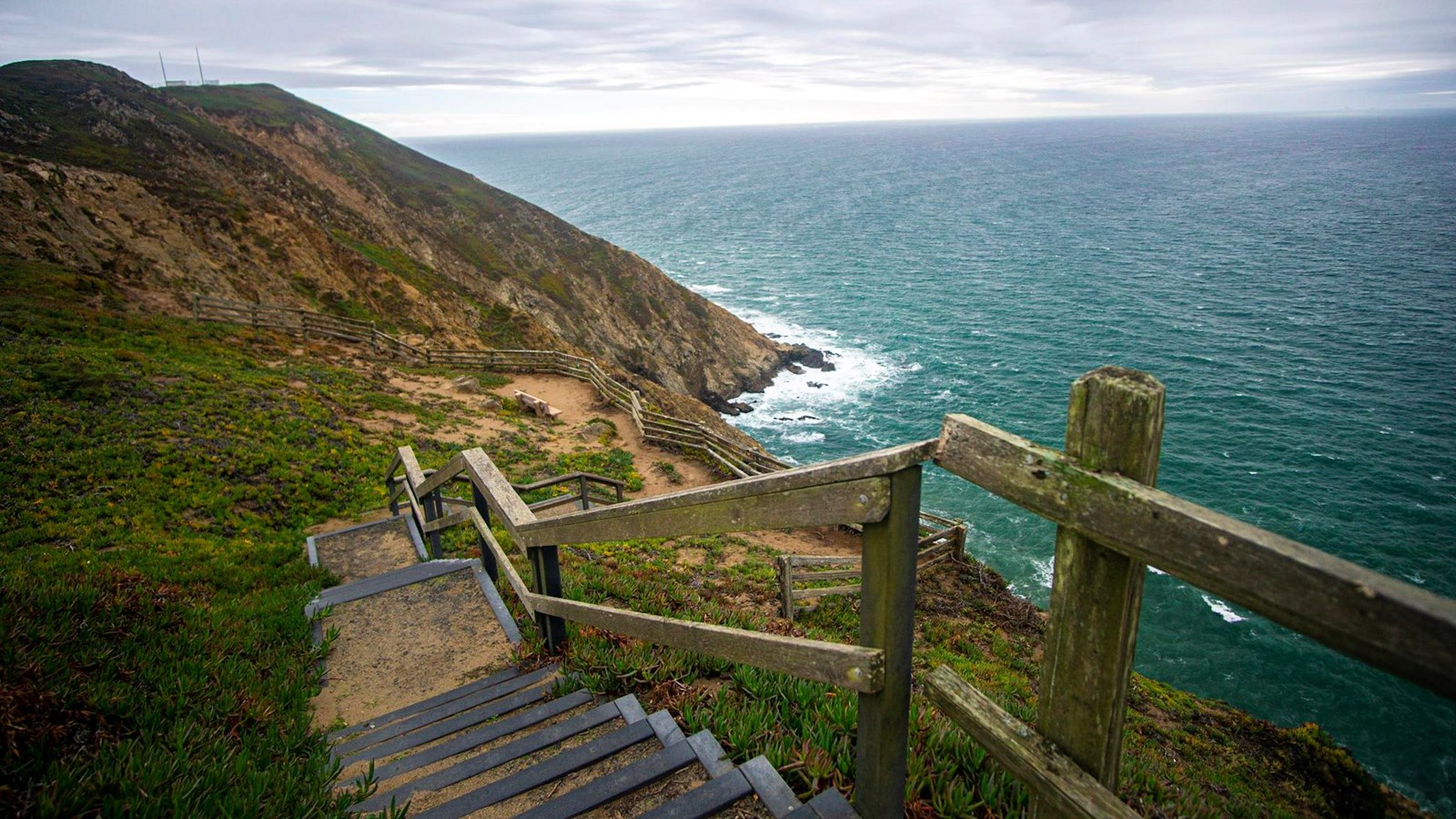 Steps lead down to an overlook above a rocky cliff side.