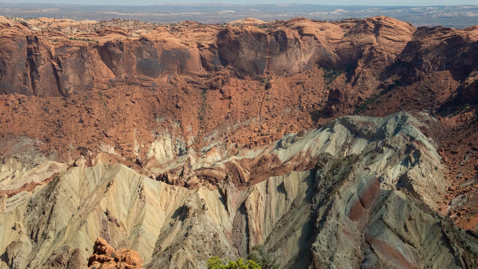 Layers of green, red, beige and orange rock are visible within a crater.
