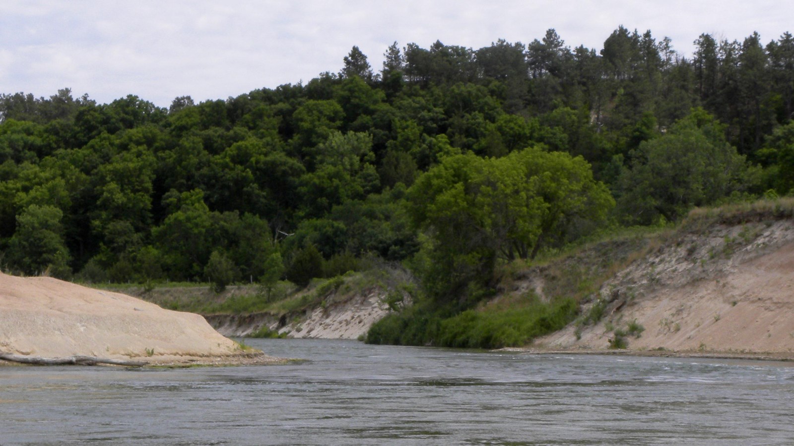 A river is pinched into a channel with stony, steep banks.