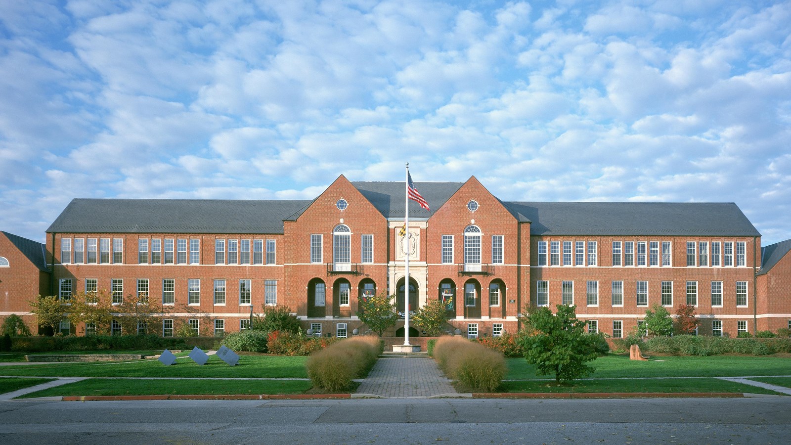 A large brick building with symmetrical design set against a partly cloudy sky.