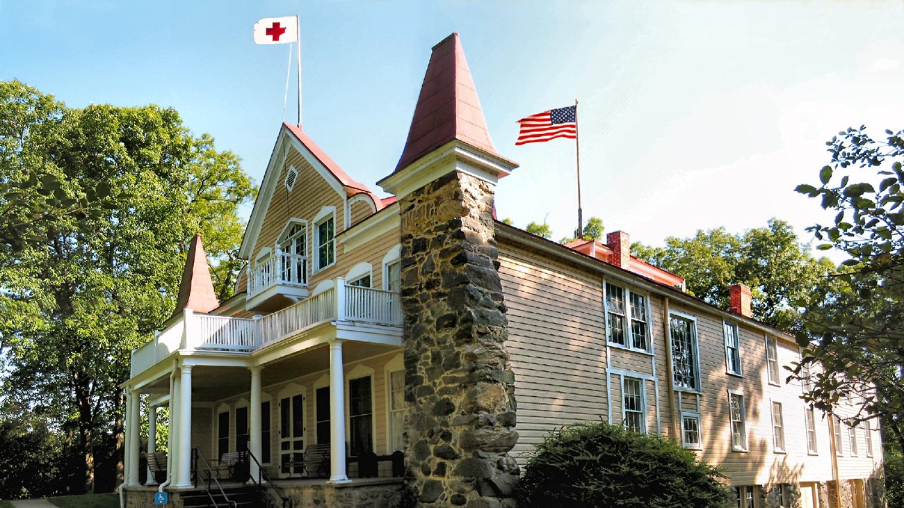 A large Victorian home with Red Cross flag flying at the top.