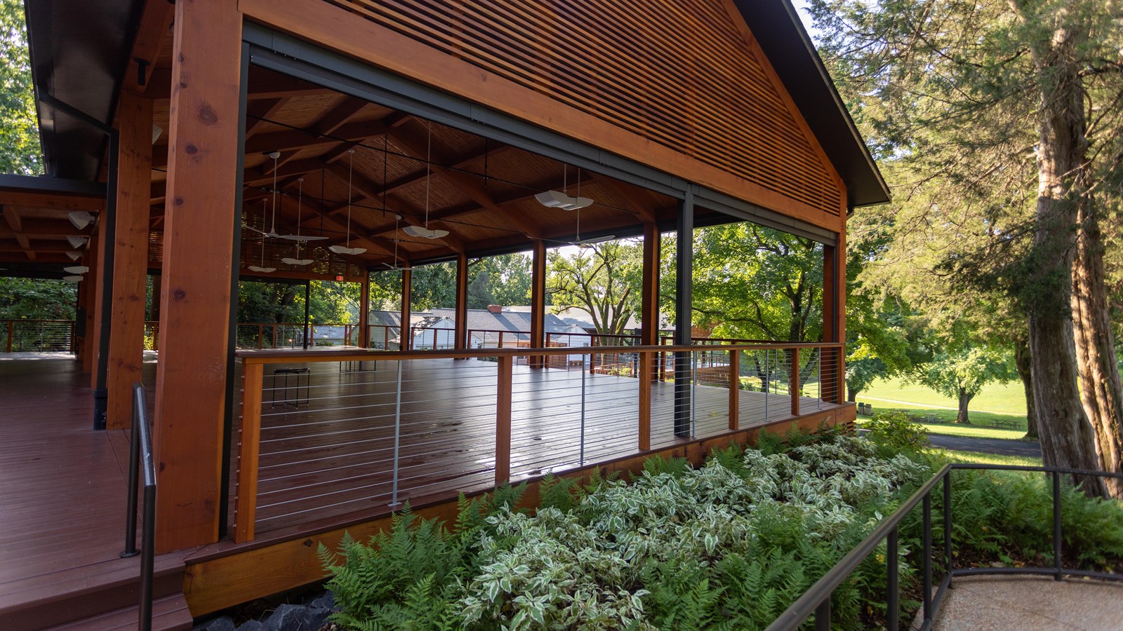 A covered wooden pavilion with ferns along the edge and a ramp.