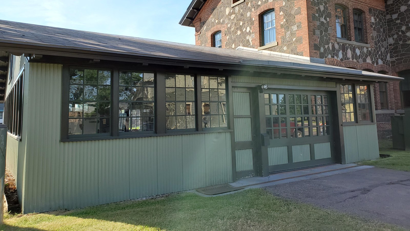 Single story building with single-gable roof and green siding.