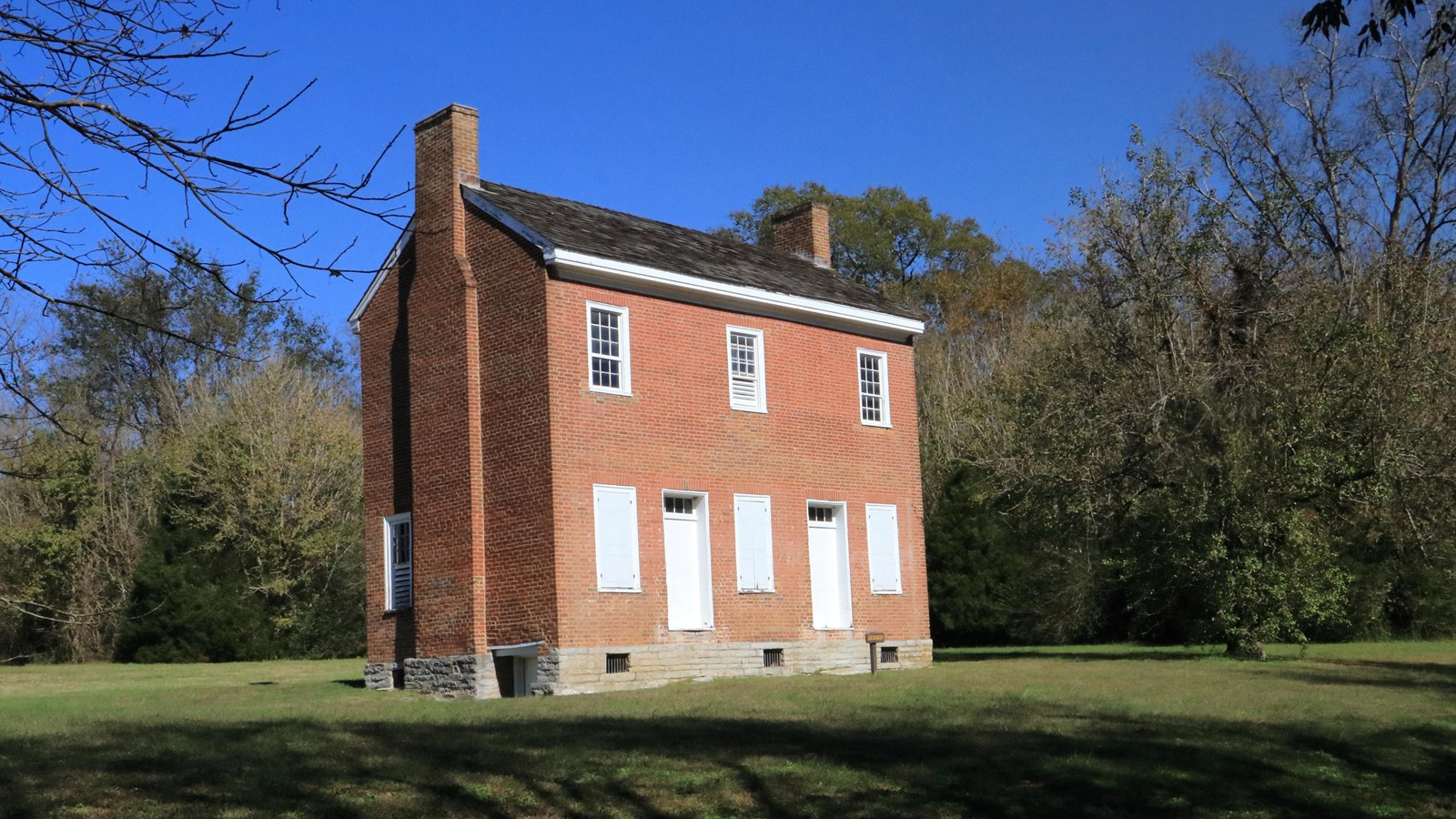 two story brick home with two white doors on the front. A total of 6 windows, 3 on the first floor.