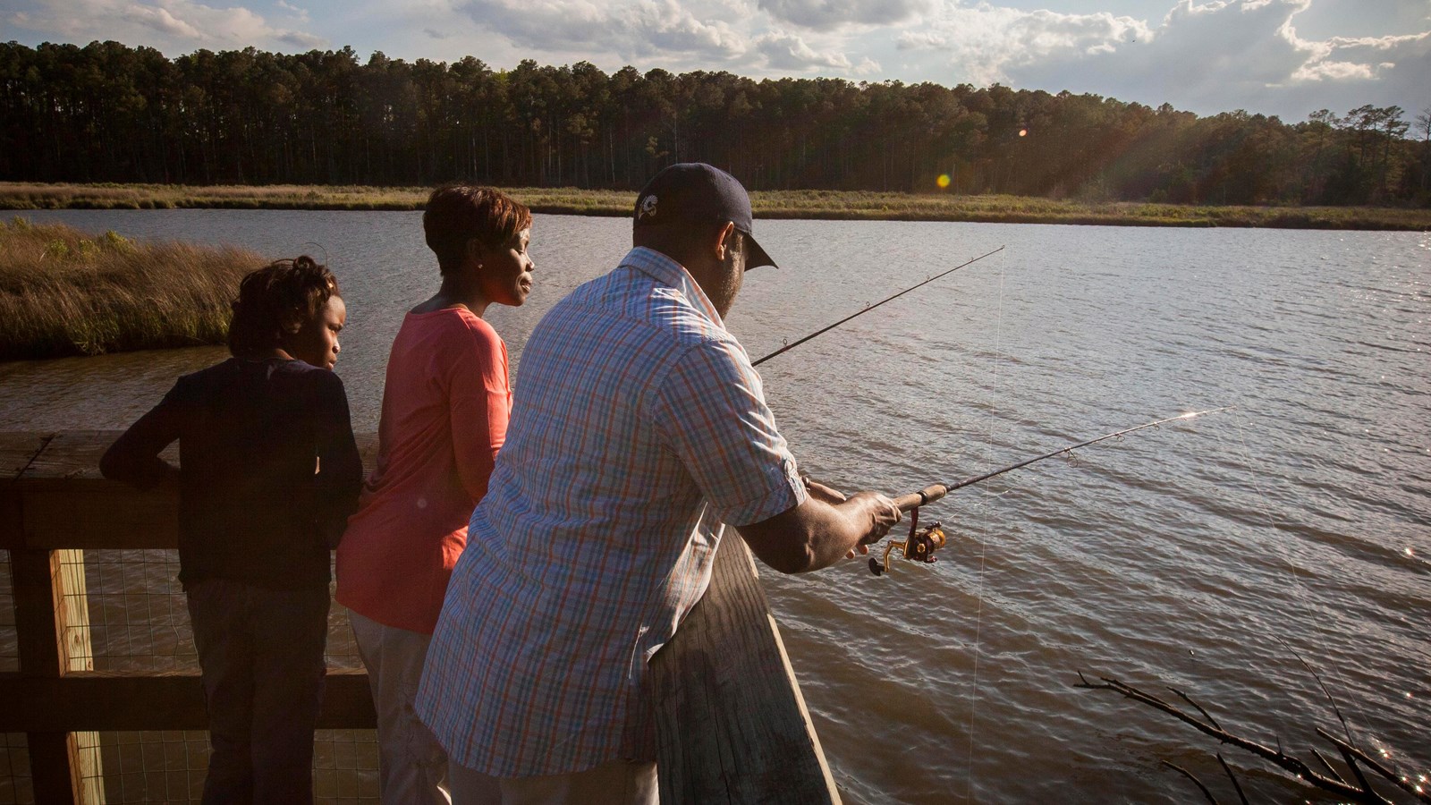 A family fishing from a pier overlooking a river. 