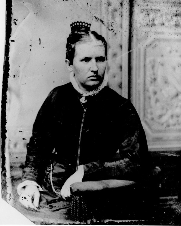 A young woman poses for a studio portrait in a late 19th century photo.