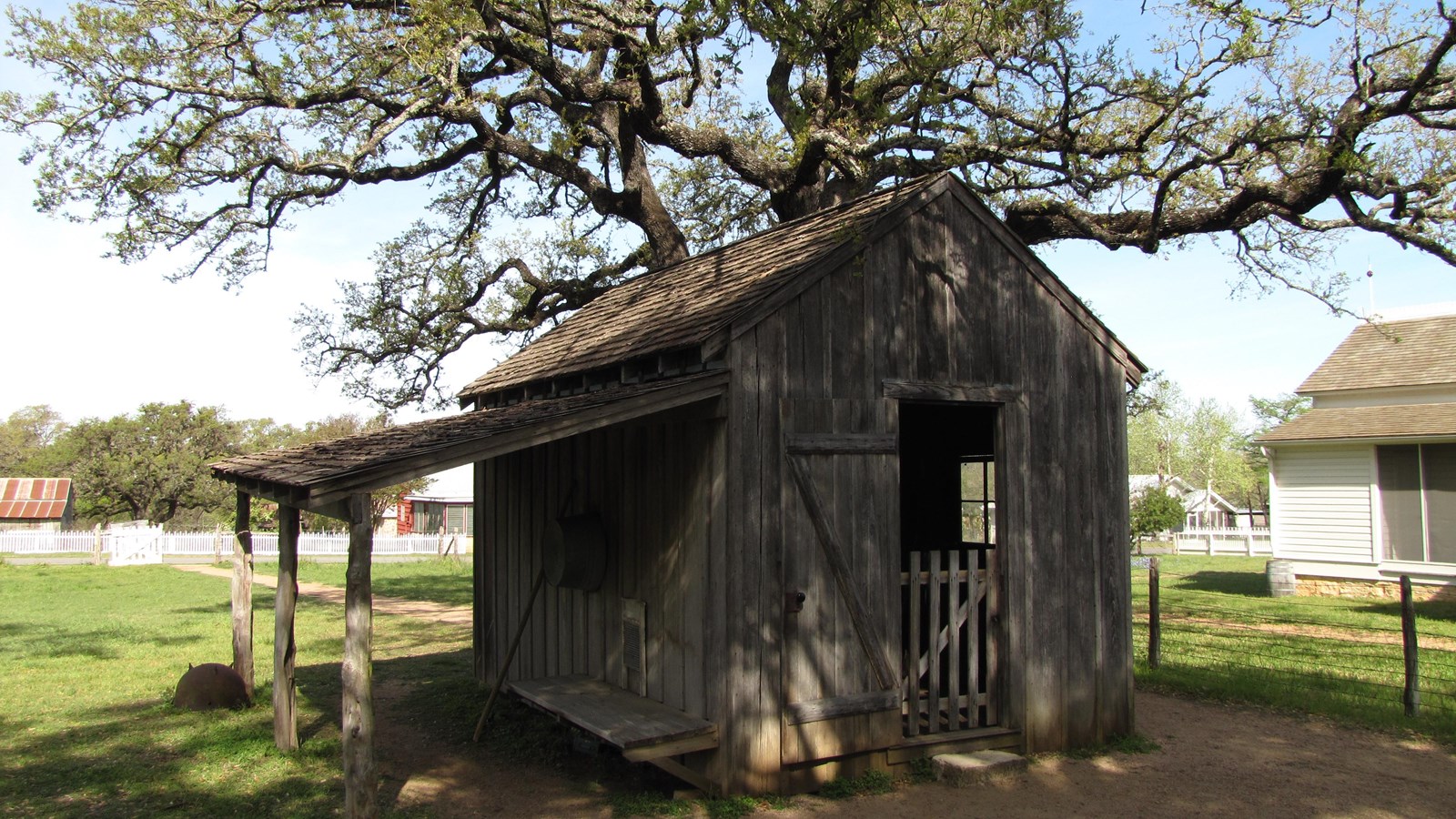 A large wooden structure sits in the backyard with its door and lean-to shed open.