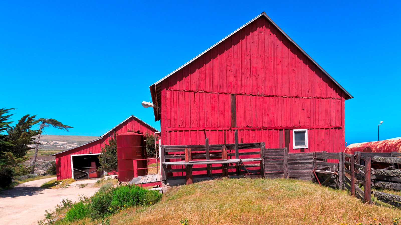 two larger barns with fence around them.