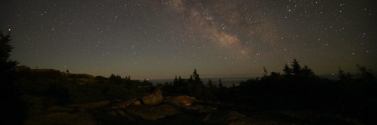 Milky way over a mountain summit and trees